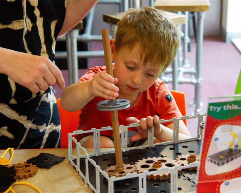 Young boy putting a crane together at a Workbench