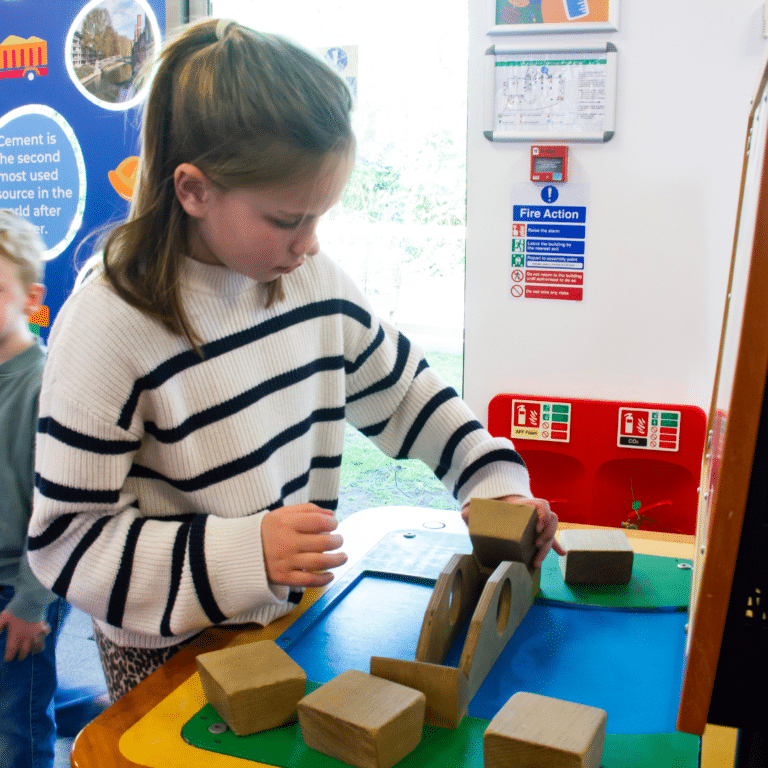 A girl puts the pieces in place on an arch bridge