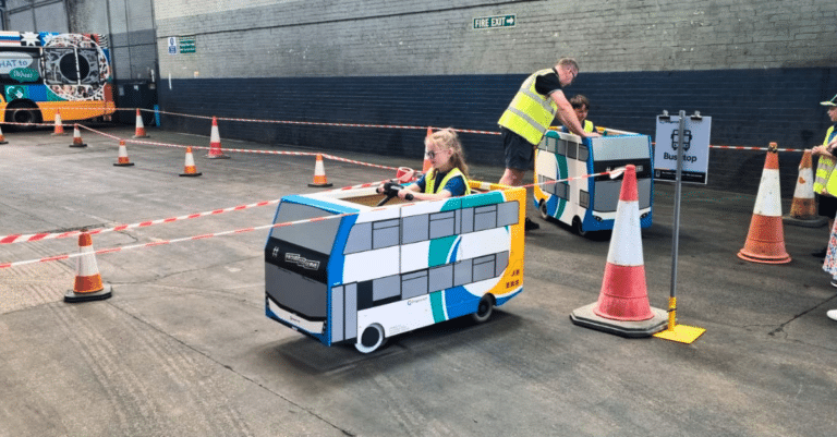 A girl drives a mini-bus around a route as school children get Behind the Buses!