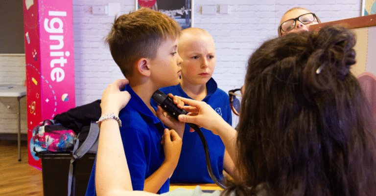 Boy tries out the vocal vibration sounding machine - one of the hands-on STEM exhibits
