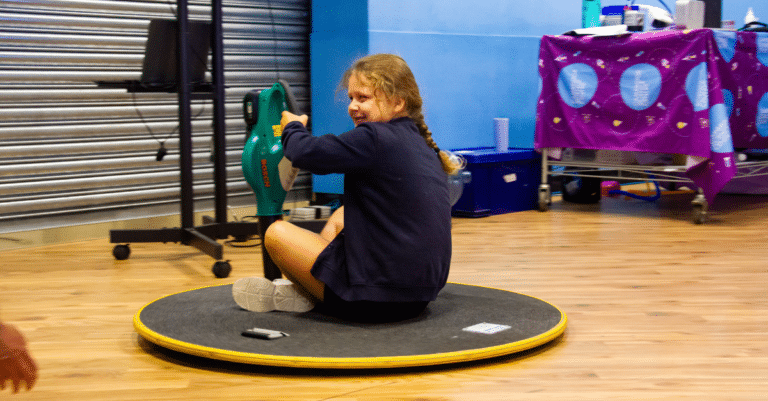A girl on a hovercraft powered by a leaf blower at Cambridge Science Centre