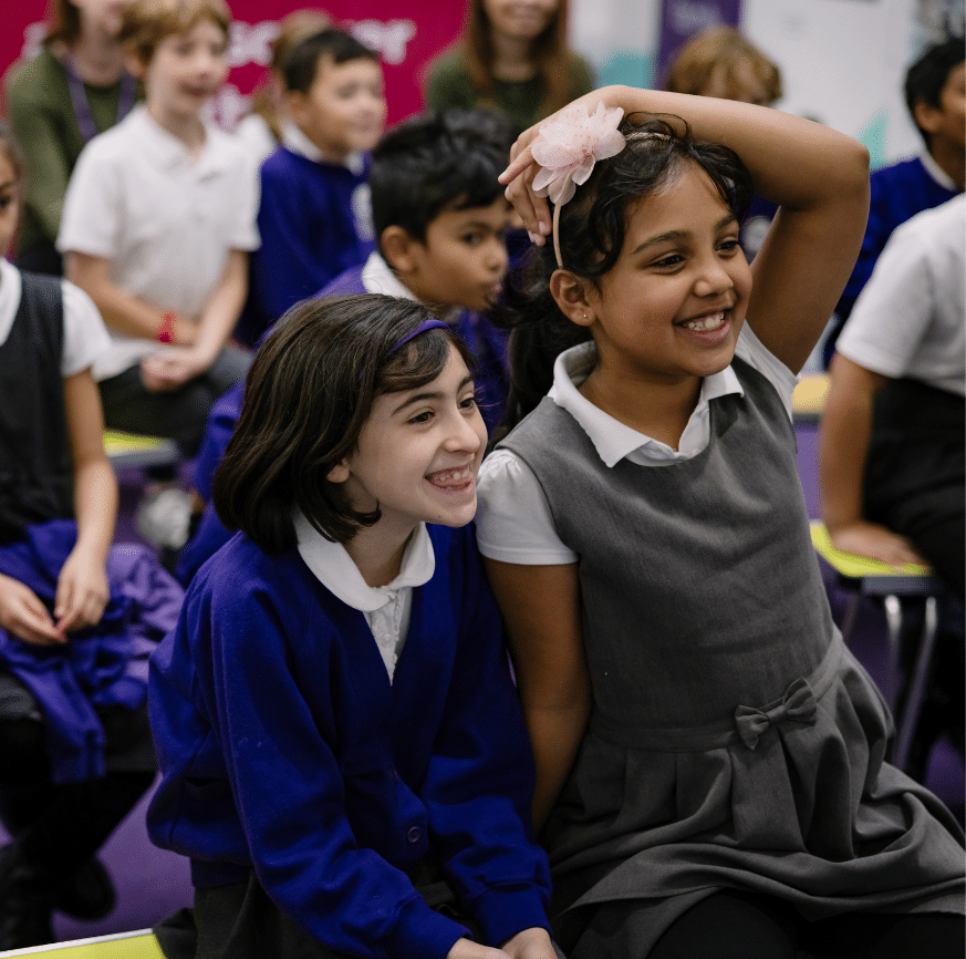 School children sit in rows with two at the front smiling at the show