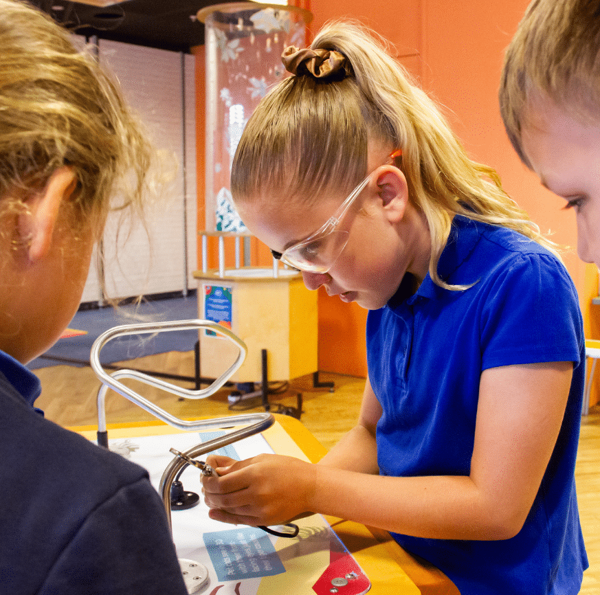 A girl in safety glasses (one eye blocked) tried to beat the beeps with a steady hand on an 'eye-hand coordination STEM exhibit in Wisbech